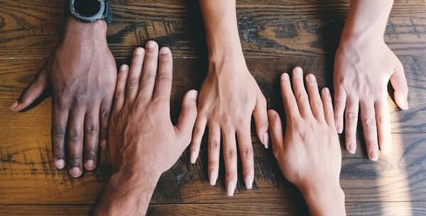 five human hands on brown surface